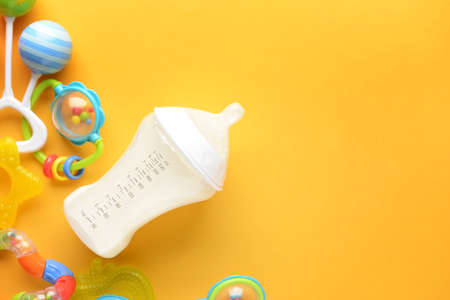Bottle of milk for baby and toys on color backgroundの写真素材
