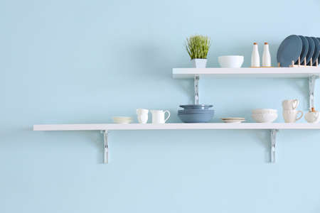 Shelves with tableware hanging on color wallの写真素材