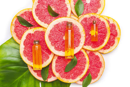 Bottles of essential oil and grapefruit slices on white backgroundの写真素材
