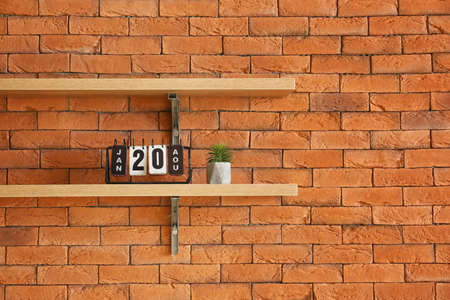 Shelves with calendar and houseplant hanging on brick wallの写真素材