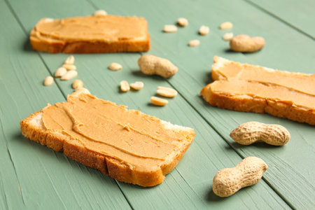 Slices of bread with tasty peanut butter on color wooden backgroundの写真素材