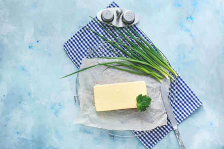 Tasty butter and green onion on color background