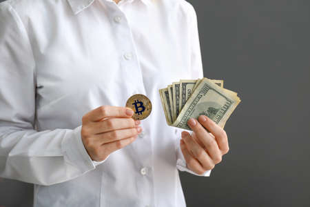 Woman with bitcoin and dollar banknotes on gray backgroundの写真素材