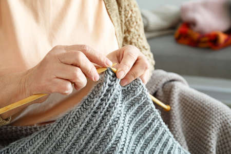 Senior woman knitting warm sweater at home, closeup