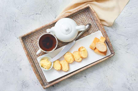Tray with tasty bread, butter and tea on white background