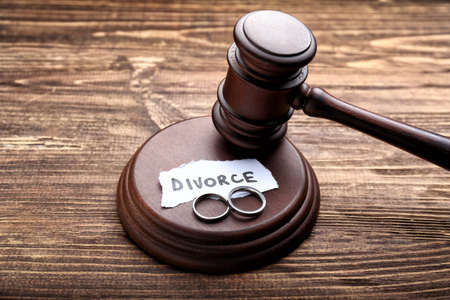 Judge's gavel, rings and paper with word DIVORCE on wooden background