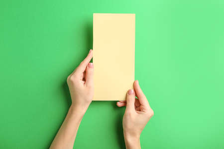 Female hands with blank menu on color backgroundの写真素材