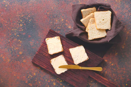 Board with tasty bread and butter on color background