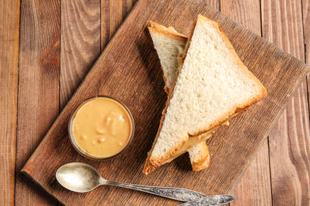 Fresh bread with tasty peanut butter on wooden table