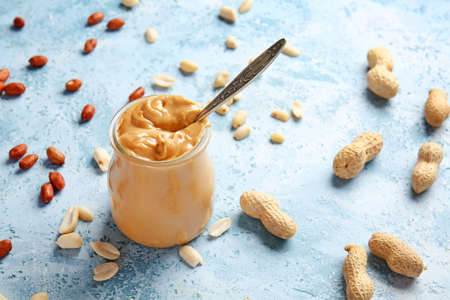 Tasty peanut butter in jar on color backgroundの写真素材