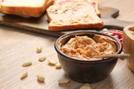 Tasty peanut butter in bowl on wooden table