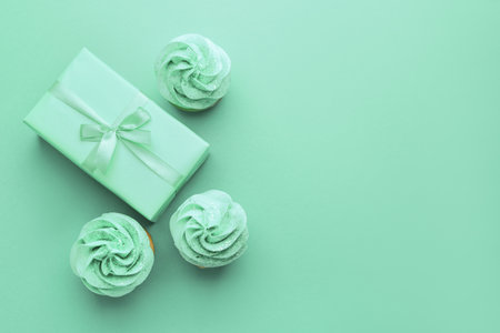 Tasty cupcakes and gift on turquoise backgroundの写真素材