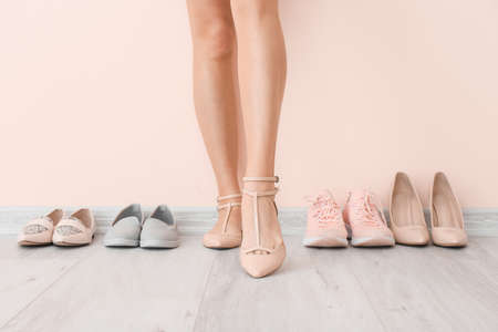 Young woman with different stylish shoes near light wallの写真素材
