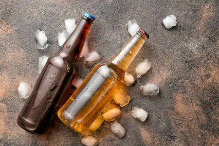 Bottles of fresh beer and ice cubes on grunge backgroundの写真素材