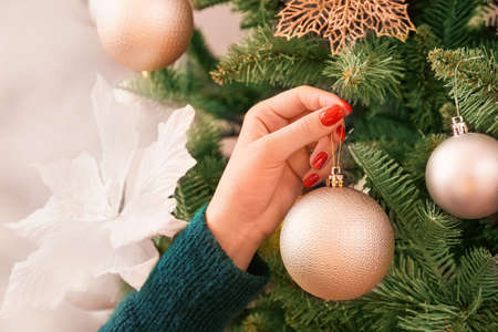 Woman decorating Christmas tree at home, closeup