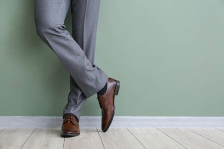 Young man in stylish shoes near color wallの写真素材