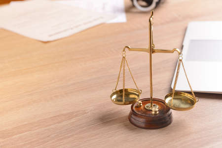 Scales of justice with laptop on lawyer's workplace