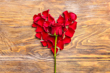 Rose and heart made of petals on wooden background. Valentine's day celebrationの写真素材