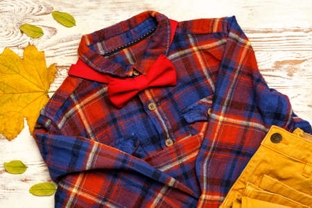 Stylish autumn kid clothes on white wooden background