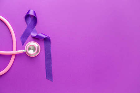 Stethoscope and purple ribbon as symbol of World Cancer Day on color backgroundの写真素材