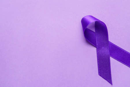 Purple ribbon as symbol of World Cancer Day on color background