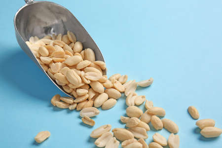 Scoop with peanuts on color background