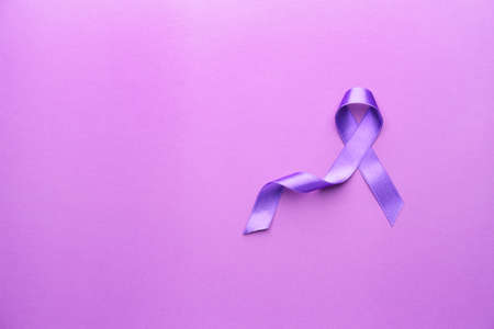 Purple ribbon as symbol of World Cancer Day on color backgroundの写真素材