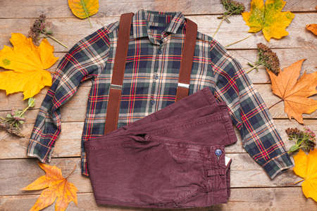 Stylish autumn kid clothes with leaves on wooden background