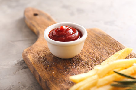 Tasty french fries and tomato sauce on wooden boardの写真素材