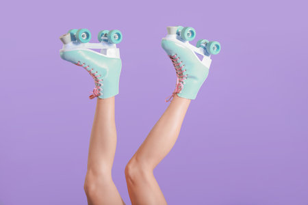 Legs of young woman on roller skates against color background