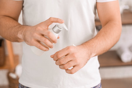 Handsome young man applying cream on his hand in bathroom, closeupの写真素材