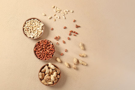 Bowls with peanuts on color background