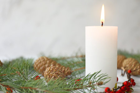 Glowing candle with Christmas decor on white backgroundの写真素材