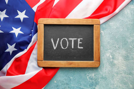 Chalkboard with text VOTE and USA flag on color background