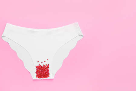 Female panties with red beads on color background. Menstruation conceptの写真素材
