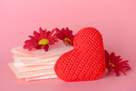 Menstrual pads with red heart and flowers on color background. Menstruation conceptの写真素材