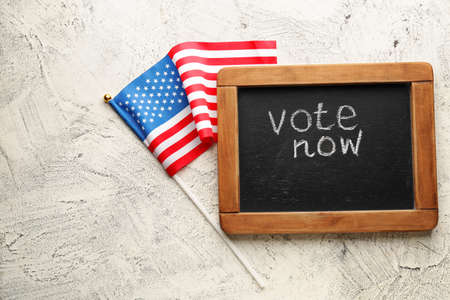Chalkboard with text VOTE NOW and USA flag on light backgroundの写真素材