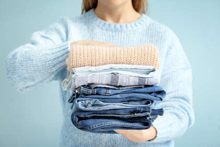 Woman with stack of warm clothes on color backgroundの写真素材