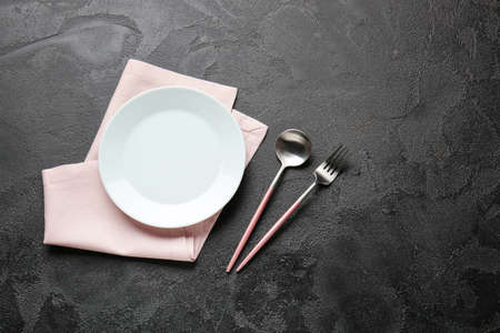 Empty plate and cutlery on dark background