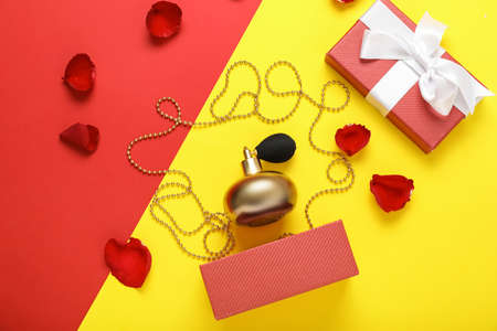Bottle of perfume, gift box and flower petals on color backgroundの写真素材