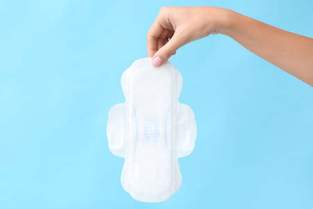 Female hand with menstrual pad on color backgroundの写真素材
