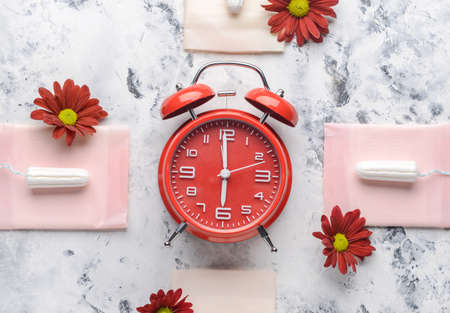 Menstrual pads with tampons and alarm clock on white background. Menstruation conceptの写真素材