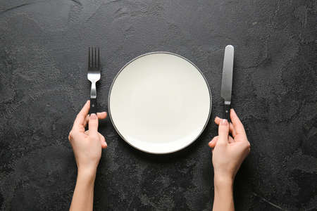 Woman with empty plate and cutlery at table