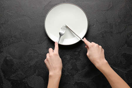 Woman with empty plate and cutlery at tableの写真素材