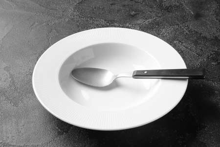 Empty plate and spoon on dark backgroundの写真素材