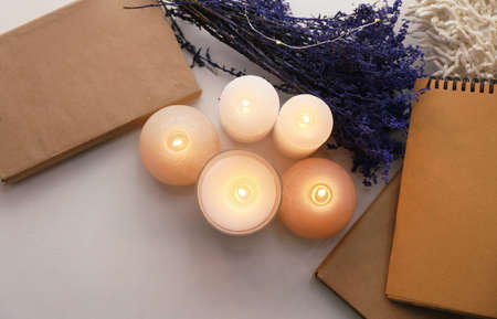 Beautiful burning candles, flowers and notebooks on tableの写真素材
