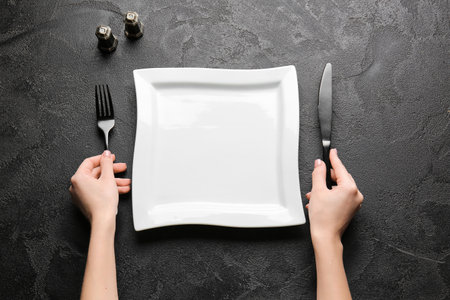 Woman with empty plate and cutlery at tableの写真素材