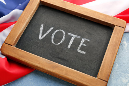 Chalkboard with text VOTE and USA flag on color backgroundの写真素材