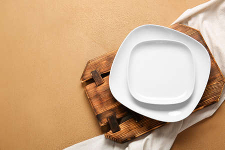 Empty plates, board and napkin on color backgroundの写真素材