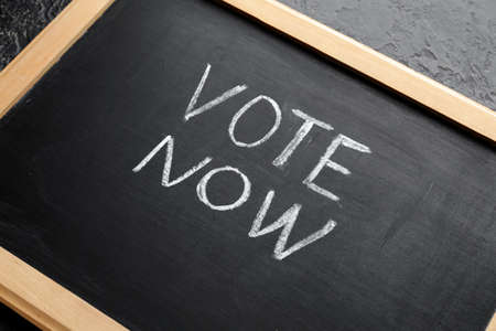 Chalkboard with text VOTE NOW on dark background, closeupの写真素材